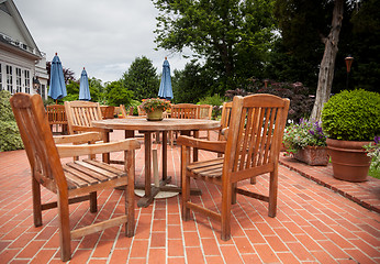 Image showing Teak patio tables and chairs on brick deck