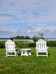 Image showing Single senior man in white chairs overlooking bay