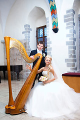 Image showing groom and bride with harp in old town hall interior