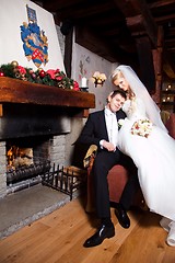 Image showing beautiful groom and bride  sitting near fireplace