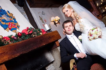 Image showing beautiful groom and bride  sitting near fireplace