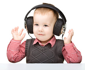 Image showing Cute little boy enjoying music using headphones