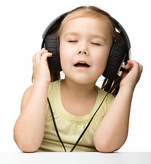 Image showing Cute little girl enjoying music using headphones