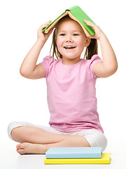 Image showing Cute little girl is hiding under a book