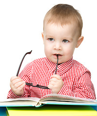 Image showing Little child play with book and glasses