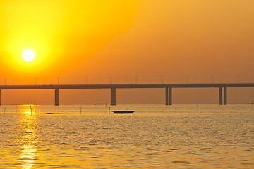 Image showing Sunset over a bridge with moving boats