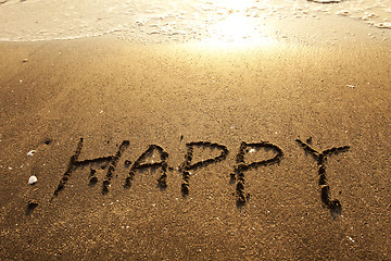 Image showing Happy handwritten words on sand