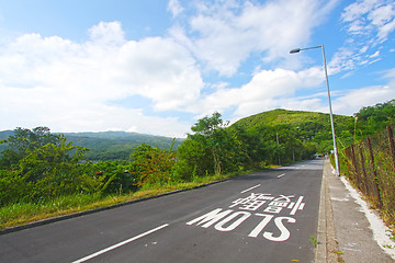 Image showing Road in a meadow against the blue sky with white clouds 