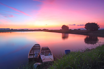 Image showing Sunset along the pond with isolated boats 