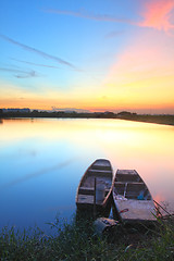 Image showing Sunset with isolated boats in water body