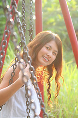 Image showing A beautiful and cheerful asian girl playing swing