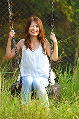 Image showing Asian girl playing swing in a park