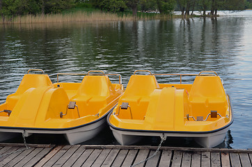 Image showing Yellow water bicycles locked at lake pier 