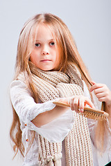 Image showing Cute girl combing long blond hair