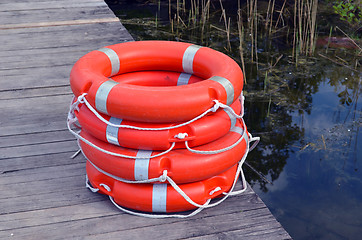 Image showing Life savers buoys orange stack wooden lake pier 