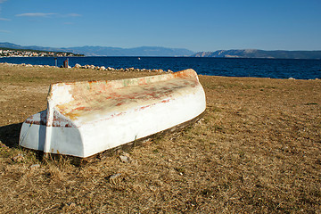 Image showing old boat stranded on stone beach