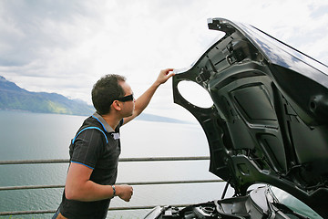 Image showing man having a bad day checks his car to figure out what the probl