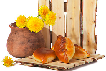 Image showing three pies and dandelions in  clay pot