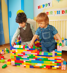 Image showing Kids building a wall of plastic blocks
