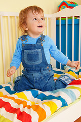 Image showing Happy toddler sitting in the baby cot