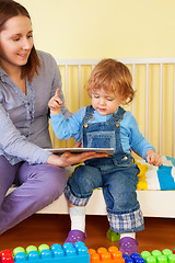 Image showing Kid sitting with mother and pointing to the picture