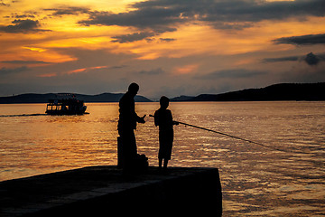 Image showing Silhouettes of father and his son fishing on sea