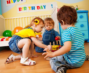 Image showing Two boys and girl playing with toy pyramid puzzle