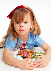 Image showing Greedy  girl with pile of sweets