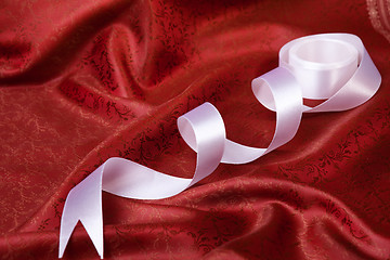 Image showing White ribbon on red drape