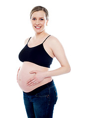 Image showing Smiling pregnant woman caressing her belly