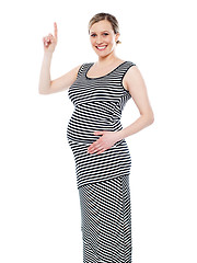 Image showing Pregnant woman pointing up at copyspace