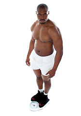 Image showing Muscular man standing on electronic weighing machine