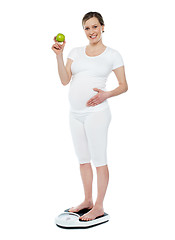 Image showing Pregnant woman standing on weighing machine