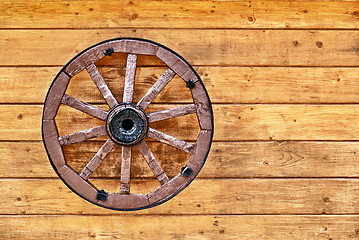 Image showing Old wagon wheel on a wooden wall