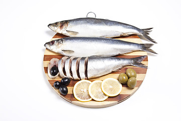 Image showing Fish with lemon and olive on wooden plate