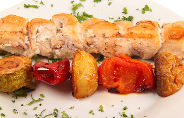 Image showing grilled meat pieces on wood sticks with vegetables close up