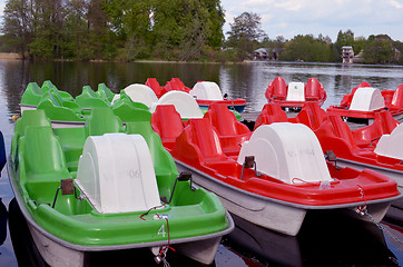 Image showing Water bicycles green and red locked at lake pier 