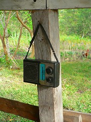 Image showing Old transistor radio hanging on wooden post