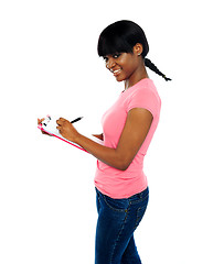 Image showing Smiling girl writing on clipboard