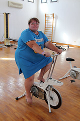 Image showing overweight woman exercising on bike