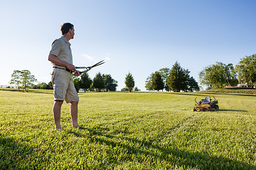 Image showing Senior man cutting grass with shears