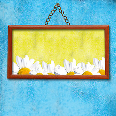 Image showing Picture frame hanging photo of daisies in an old blue wall
