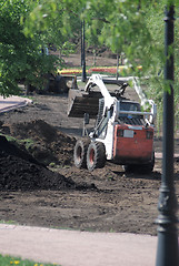 Image showing mini wheel excavator working in city park at the spring