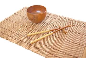 Image showing Chopsticks with wooden bowl on bamboo matting background 