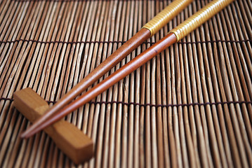 Image showing Chopsticks on brown bamboo matting background  