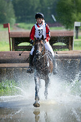 Image showing Woman eventer on horse is run in Water jump