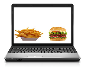 Image showing Laptop computer close-up with an hamburger and french fries