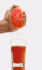 Image showing Pouring orange juice from orange into the glass