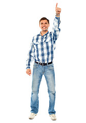 Image showing Happy young guy pointing upwards. Full shot