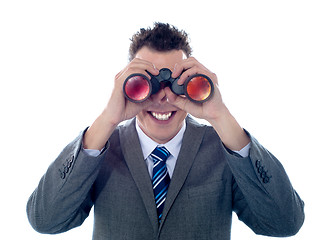 Image showing Smiling businessman looks through binoculars